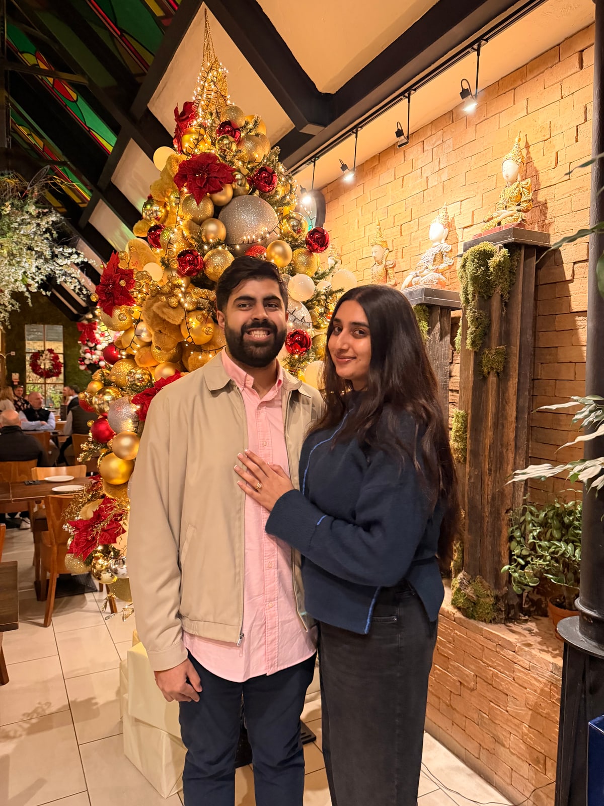 Milan and Gurleen together beside a Christmas tree in London